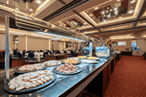 Ontbijtbuffet met diverse vleeswaren en kazen, geserveerd in een stijlvol restaurant met ronde tafels en moderne plafondverlichting.