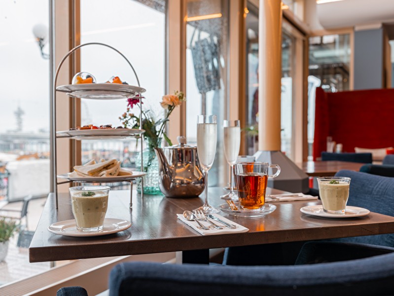 High Tea bij Grand Hotel Amrâth Kurhaus met etagère vol zoete en hartige lekkernijen, thee en champagne, met uitzicht op de Pier van Scheveningen.