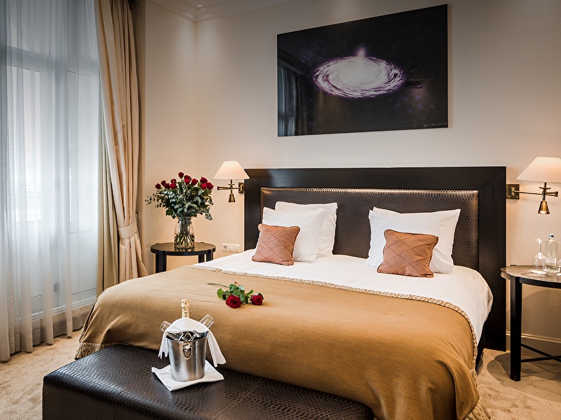 Sfeervolle hotelkamer met romantische details, rozen in de hoek, rozen op het bed en een fles champagne met twee glazen