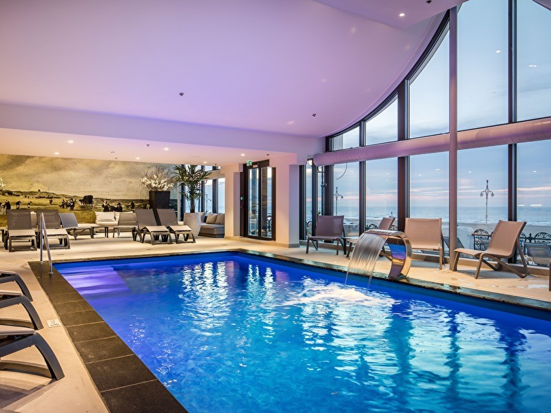 Wellness zwembad met ligbedden langs de rand en uitzicht op de Noordzee